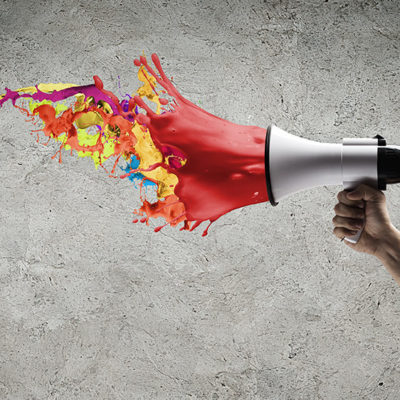 Image: Hand holding out a megaphone exploding with colorful paint